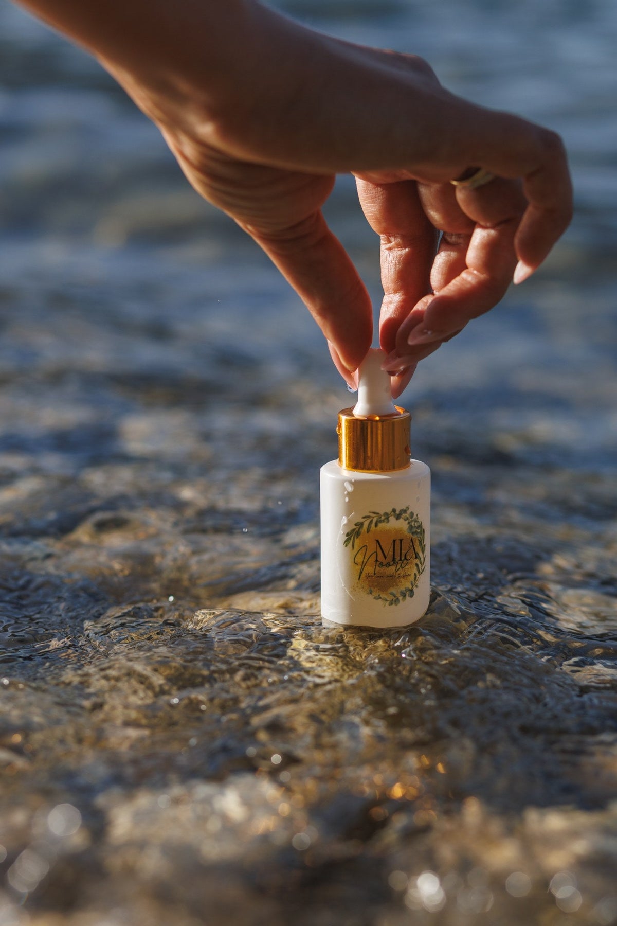 Mia Noore Balanced Harmony face oil bottle standing in clear lake water