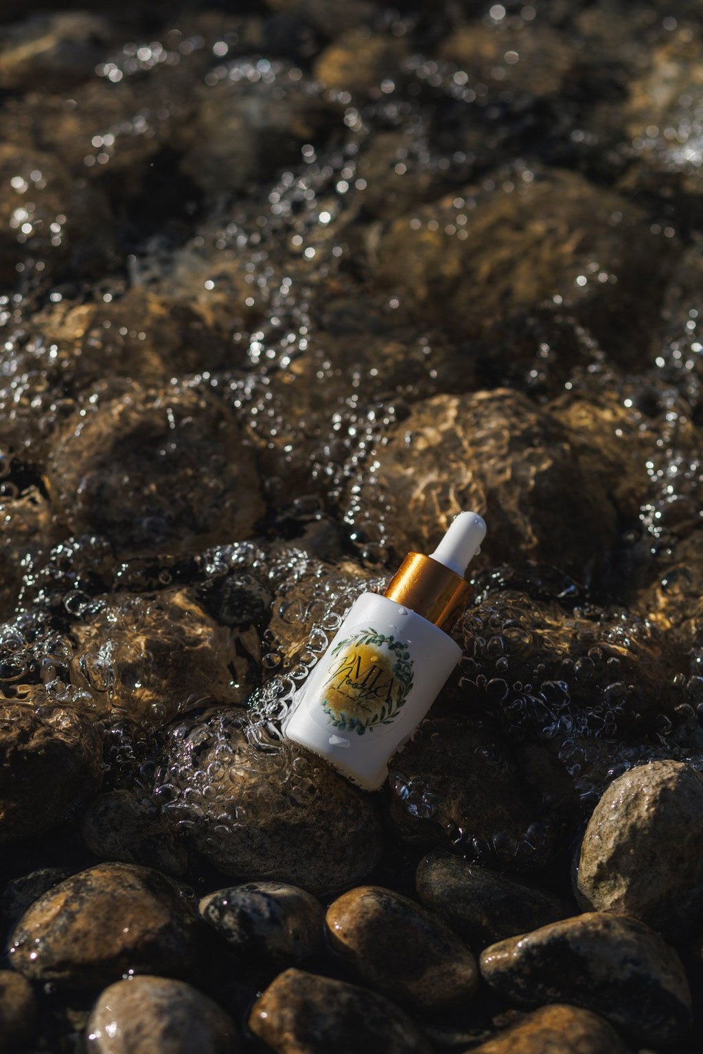 Mia Noore Balanced Harmony face oil bottle resting on wet river stones