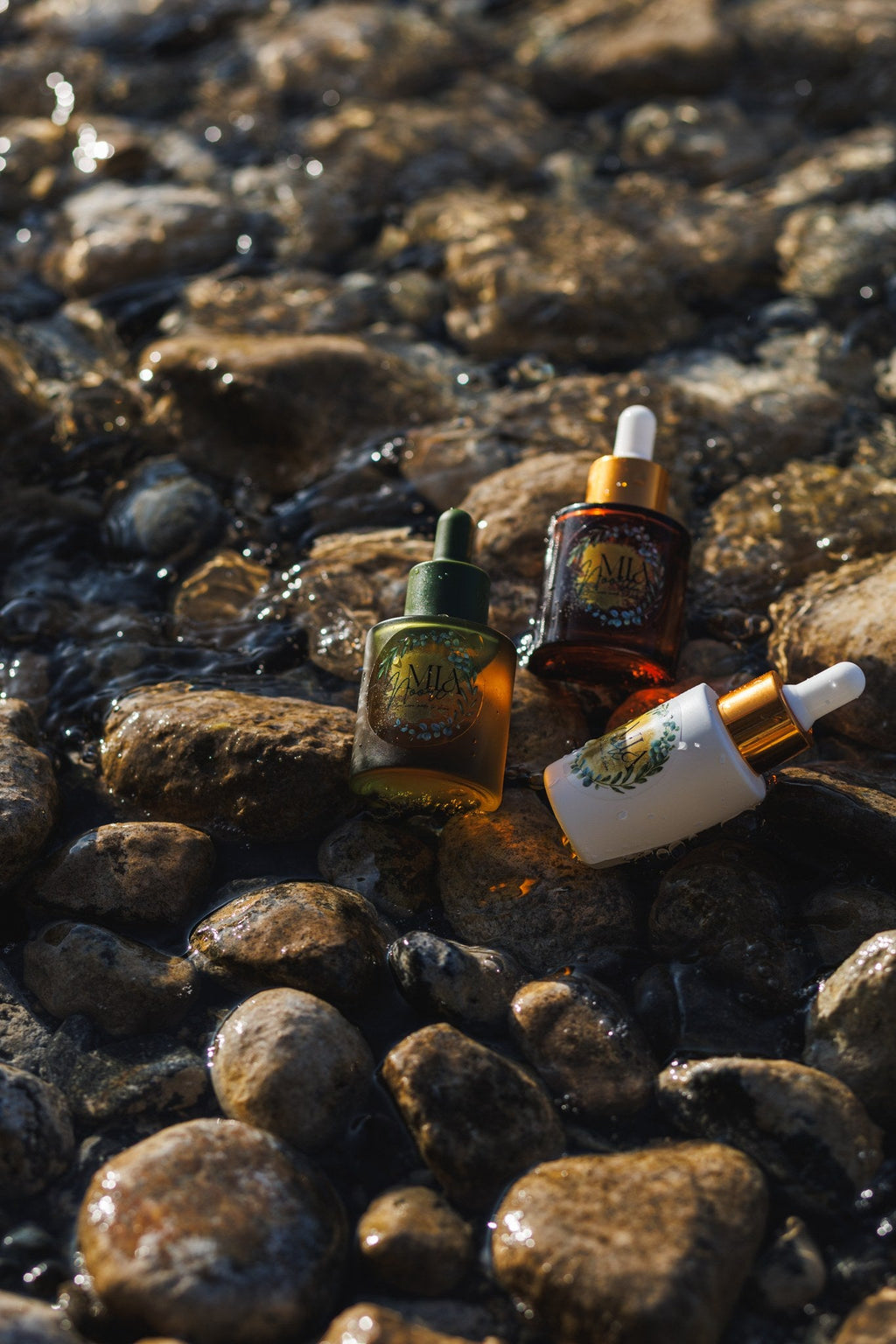 All three Mia Noore face oils - Balanced Harmony, Radiant Glow and Timeless - on river stones