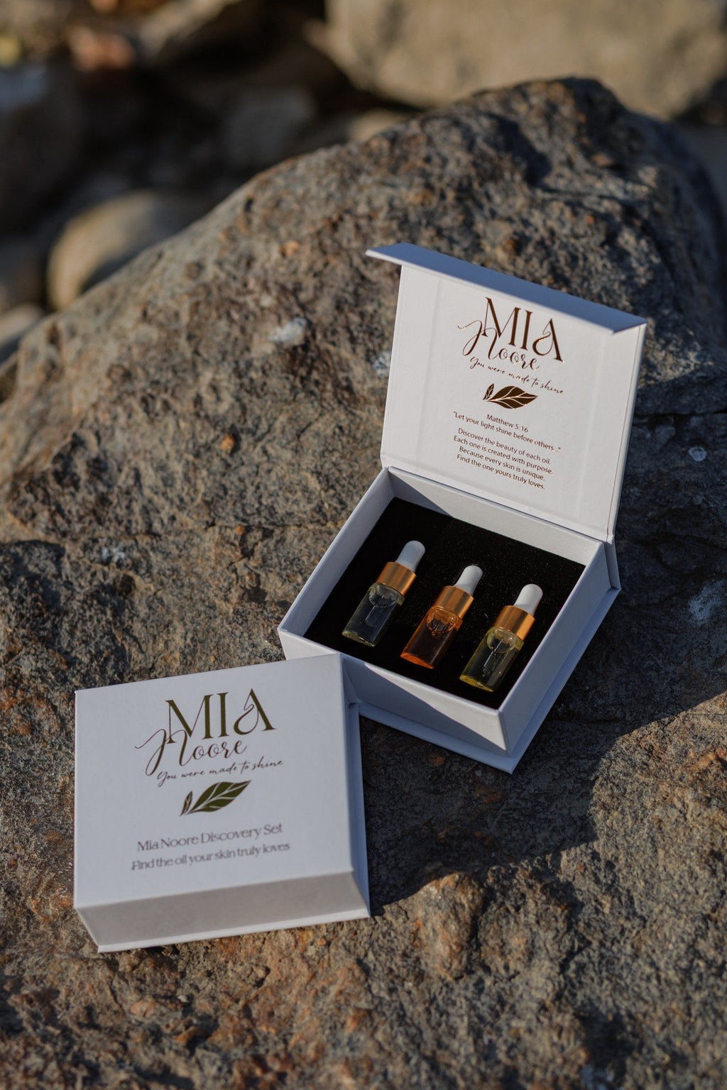 The Mia Noore Discovery Set box open on a rock, showing the three sample face oils