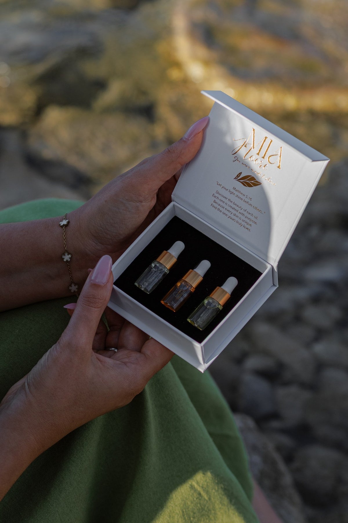 Hands holding the open Mia Noore Discovery Set with three sample face oils