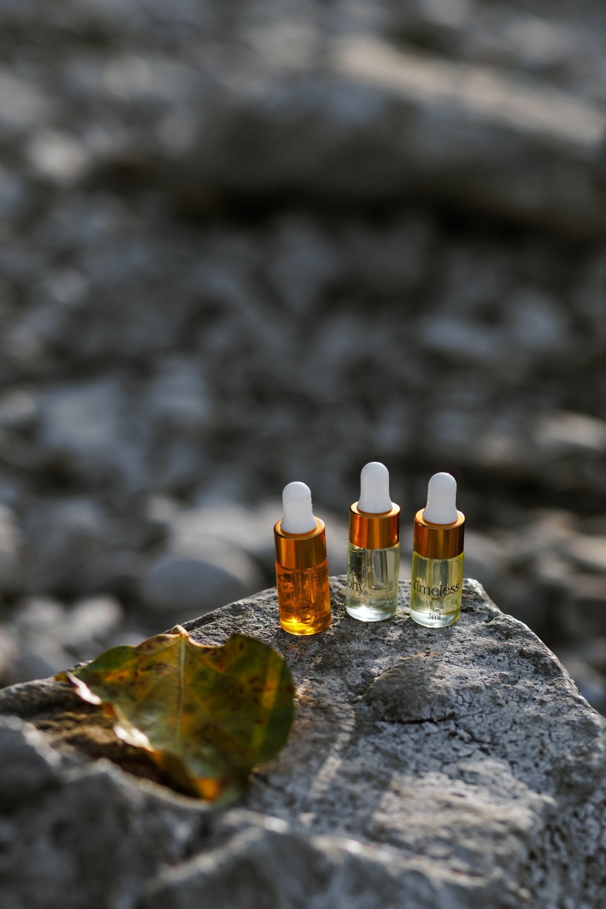 The three Mia Noore Discovery Set sample oils standing on a river stone